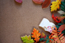 Botanical Layout On Cork Board: Leaves And Fruits Of Mountain Ash, Autumn Leaves And Gingerbread On Brown Background. Homemade Notebook And Leaves Cookies Top View