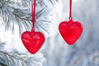Two read hearts hanging on a snow-covered pine tree, vintage glass Christmas decoration