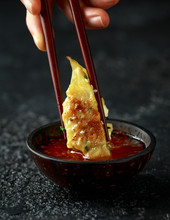 Chopsticks Holding And Dipping Meat Dumplings, Fried Yaki Gyoza In Sweet Chilli Sauce.