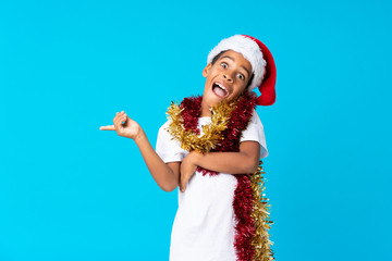 Poster - African American boy with christmas hat surprised and pointing finger to the side