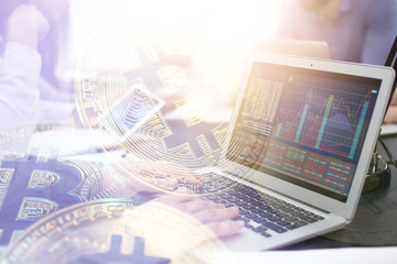 Double exposure of young man using laptop and golden bitcoins