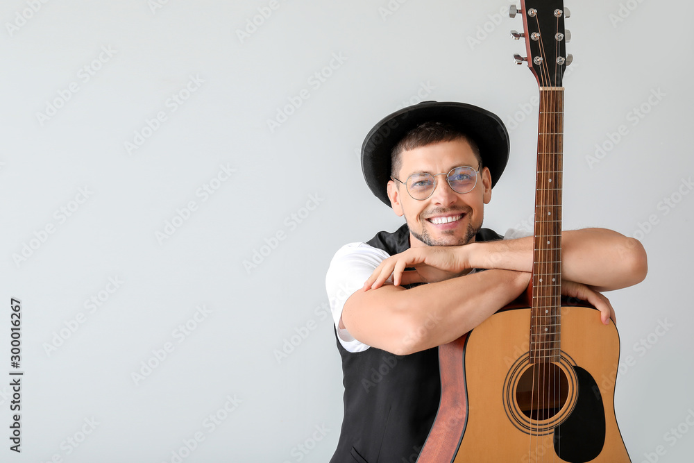 Handsome man with guitar on light background