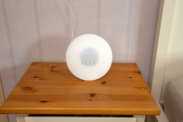 Wake-up light modern alarm on wooden night stand in retro living room