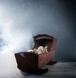 Scary abandoned old baby doll in a cradle with mist