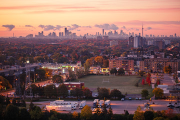 Beautiful pink yellow red purple morning sky clouds in Toronto city, Canada. Rays of early rising sun. Landscape aerial top view with urban street. Twilight in Canadian town at sunrise or sunset.