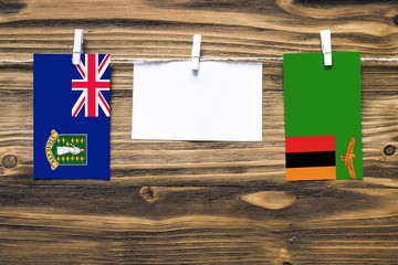 Wall Mural - Hanging flags of British Virgin Islands and Zambia attached to rope with clothes pins with copy space on white note paper on wooden background.Diplomatic relations between countries.