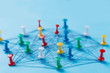 © Nana_studio - Small network of colorful pins and string, An arrangement of colorful pins linked together with string on a blue background suggesting a network of connections.