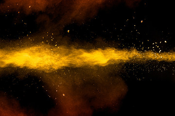 abstract yellow orange powder explosion on black background.freeze motion of yellow orange dust part