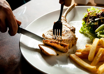 knife cutting grilled pork chops steak Close up, Pork chop steak with salad and french fries