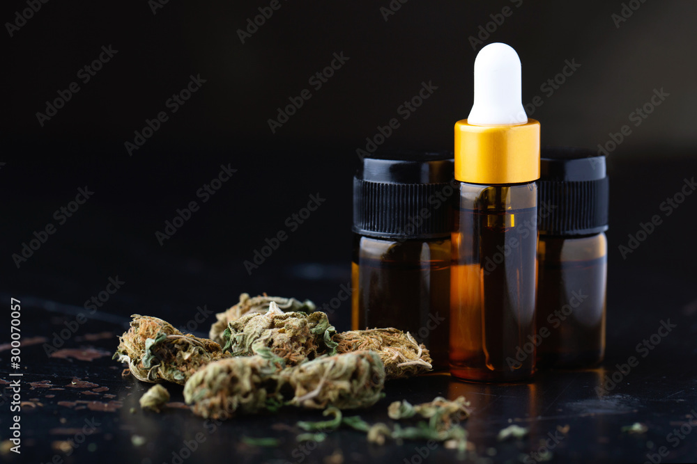 Essential oil made from medicinal cannabis.Detail of Bottle with CBD oil on black background, Cannabis Oil - medical marijuana concept - obrazy, fototapety, plakaty 