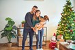 © Krakenimages.com - Young beautiful couple holding dog smiling happy and confident. Standing and hugging around christmas tree at home