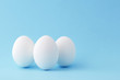 Three white chicken egg standing vertical on blue background