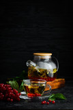 Fototapeta Kwiaty - Tea from viburnum and forest herbs. Hot winter drinks. On a black background. Top view.