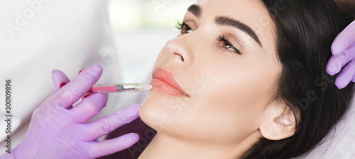 Fotografía woman having lip injections, a prick of a syringe for the beauty lips
