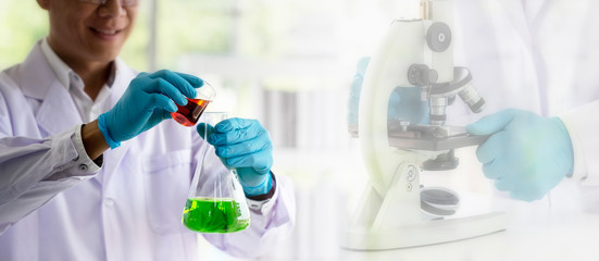 Wall Mural - laboratory concept; scientist transfer chemical reagent from beaker to flask with blurred background