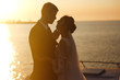 © maxbelchenko - Beautiful bride and stylish groom together on the bridge against the background of the boat at sunset. Newlyweds tenderly hug, kiss and enjoy each other at sunset. Wedding. Love. Romantic moment.
