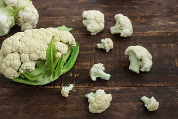 fresh harvested cauliflower on brown wooden background top view