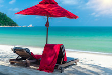 Tropical Island Beach Dream Summer Holiday Vacation Chair And Umbrella Sun Shade On A White Sand. Blue Ocean Water And Sun Shining On A Sun Bathing Chair With Red Towels.