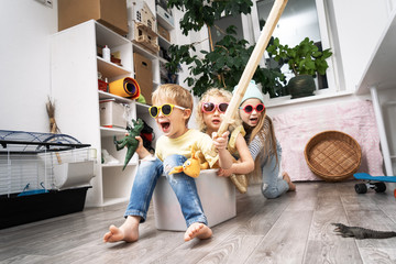 Children have fun and ride in a white plastic box. The room is a mess.