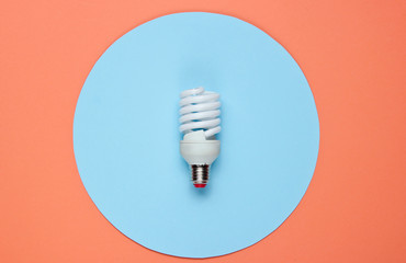 Spiral eco light bulb on a colored paper background. Top view. Minimalistic still life