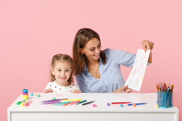 Woman child baby girl 4-5 years old draws are engaged in creativity. Mommy little kid daughter isolated on pastel pink background studio portrait. Mother's Day love family parenthood childhood concept