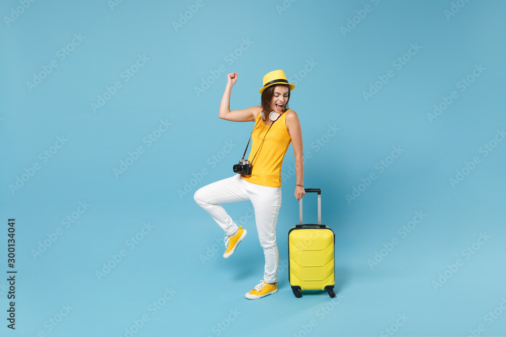 Traveler tourist woman in yellow casual clothes, hat with suitcase photo camera isolated on blue background. Female passenger traveling abroad to travel on weekends getaway. Air flight journey concept - obrazy, fototapety, plakaty 