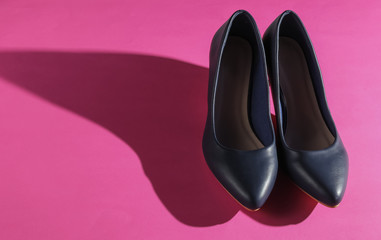 Classic women's high heel shoes on pink paper background. Stylish shoes. Studio shot. Minimalistic fashion still life.