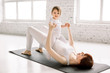 © sofiko14 - Young smiling mother doing yoga exercise at gym, wearing white sportswear, together with funny little daughter, enjoying activities with baby, fun and sport practice. Healthy lifestyle concept photo