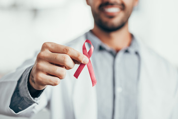 Red ribbon for HIV illness awareness in doctor's hand, 1 December World AIDS Day concept.