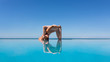 Side view of a slim woman doing marchisana on the edge of the pool against a blue sky. The concept of strengthening the arms and trains the thoracic spine. Copyspace 16:9