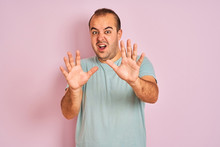 Young Man Wearing Blue Casual T-shirt Standing Over Isolated Pink Background Afraid And Terrified With Fear Expression Stop Gesture With Hands, Shouting In Shock. Panic Concept.