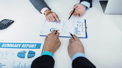 Business people pointing their hands at the data graph to analyze and plan their financial and investment strategy at meeting.