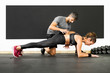 Woman doing plank with the help of a trainer