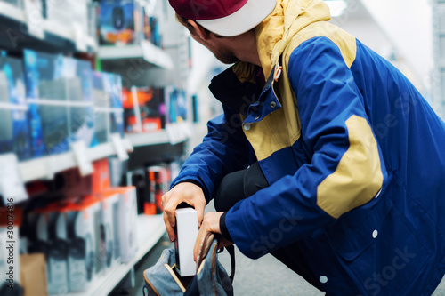 Fotomural close up consumer thief’s hands putting the new gadget in the pocket in the sto