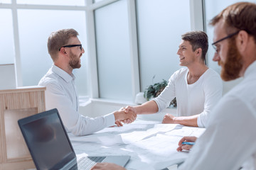 Wall Mural - business people shaking hands in a bright office.