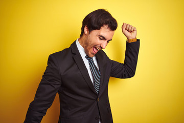 Sticker - Young handsome businessman wearing suit and tie standing over isolated yellow background Dancing happy and cheerful, smiling moving casual and confident listening to music