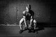 © Srdjan - Young strong fit muscular sweaty man with big muscles strength cross workout training with dumbbells weights in the gym dark image with shadows real people black and white