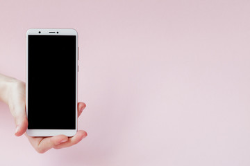 Modern mobile phone in a woman's hand on pink background