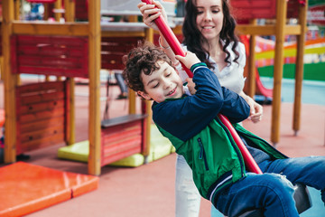 Wall Mural - Little pretty boy is having fun outdoor. Playing in children zone in amusement park.