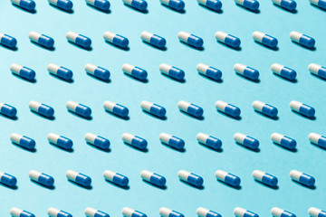 Trendy pattern made with Pharmaceutical medicine pills, tablets and capsules on bright light blue background. Medicine creative concepts. Minimal style with colorful paper backdrop. Trendy colors