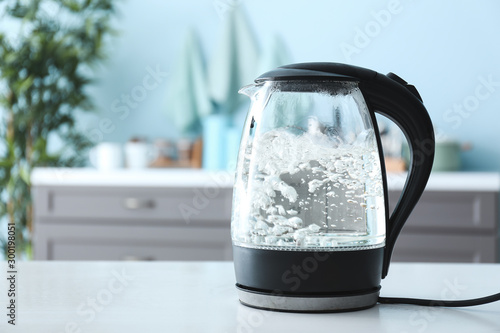 Fotomural Transparent electric kettle with boiling water on table in kitchen