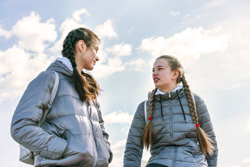 young pretty college student teen girlfriends telling outdoor blue sky with white clouds background