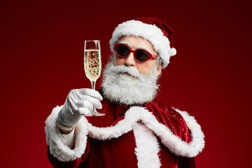 Wall Mural - Waist up portrait of modern Santa holding champagne glass while standing over red background, copy space