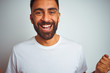 © Krakenimages.com - Young indian man wearing t-shirt standing over isolated white background celebrating surprised and amazed for success with arms raised and open eyes. Winner concept.