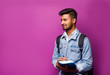 Handsome young indian student man read notebooks while standing on violet background.