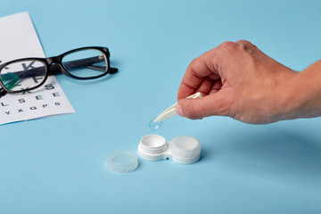 Poster - Flat composition with contact lenses, table for eye examination. Accessories for ophthalmologists. Glasses and lenses for vision correction on a blue background