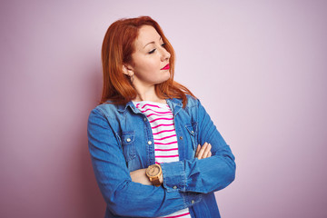 Canvas Print - Beautiful redhead woman wearing denim shirt and striped t-shirt over isolated pink background looking to the side with arms crossed convinced and confident