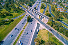Looking Down At Cars Driving On Highway Near Interchange - Aerial View