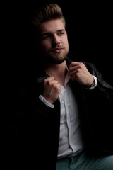 Canvas Print - casual man wearing leather jacket sitting and fixing his collar