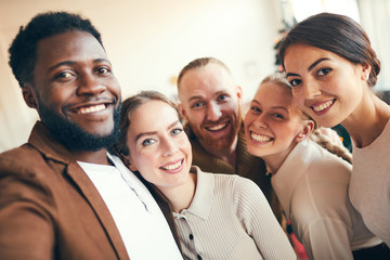 Canvas Print - Multi-ethnic group of elegant adult people smiling at camera while taking selfie photo during Christmas party